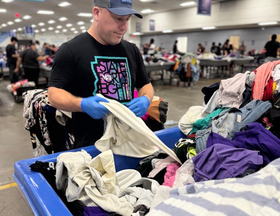 man sorting through goodwill bins with blue gloves