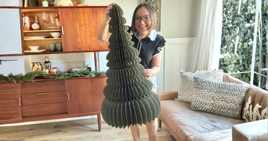 lina holding green paper christmas tree in living room
