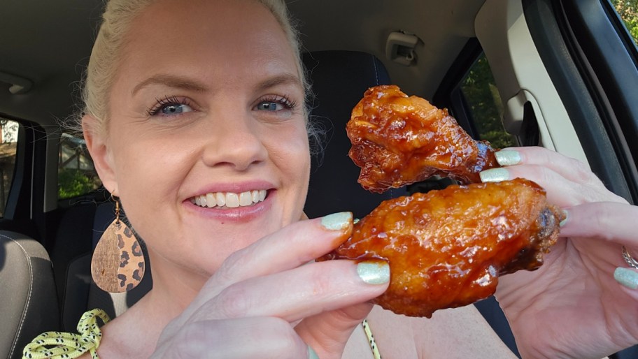 smiling woman holding two Pizza Hut chicken wings
