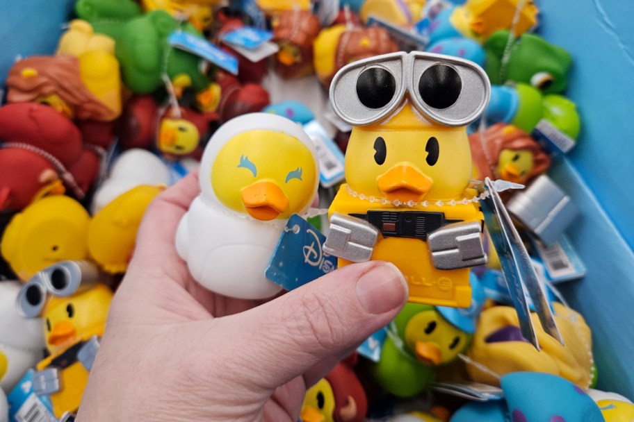 hand holding robot and white robot looking rubber ducks