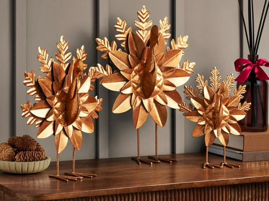 three gold metal turkey decor on table