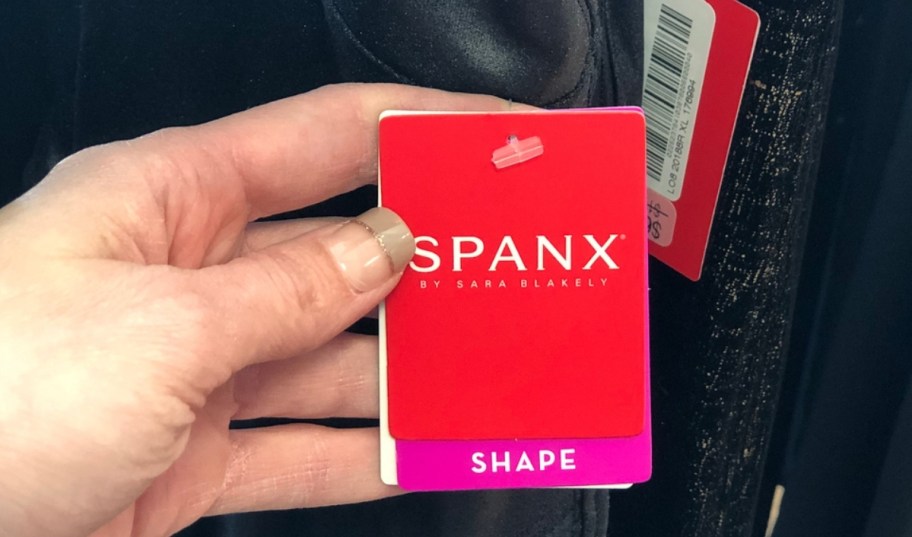 hand holding a Spanx clothing tag that's on a pair of Spanx Jeans