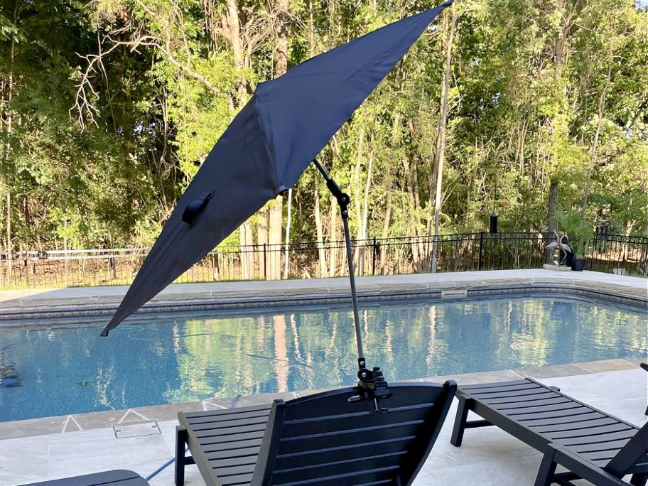 A Sport-Brella umbrella clipped to a chair by a pool.