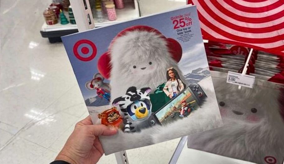 a womans hand holding the 2025 target toy catalog