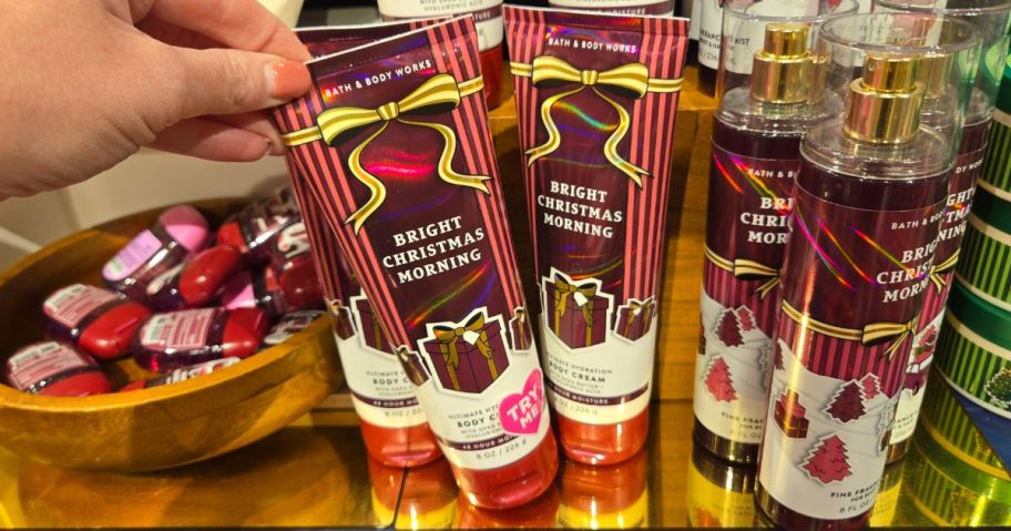 Hand touching a Bath & Body Works Body Cream in Bright Christmas Morning Scent