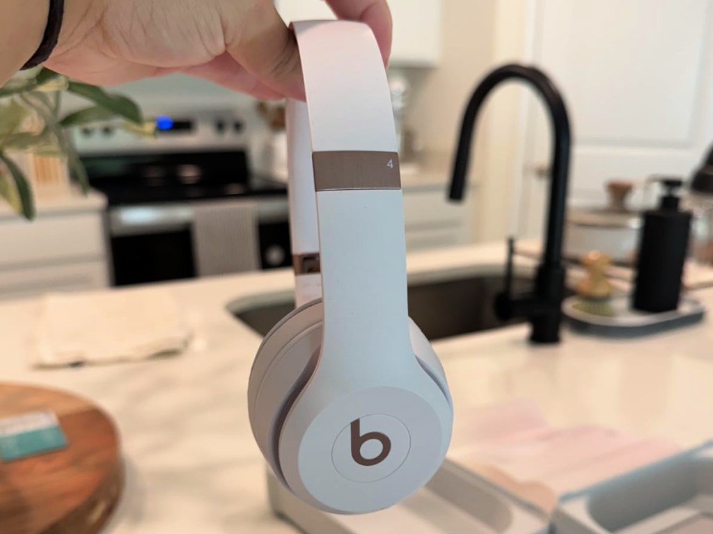 person holding white gold beats headphones