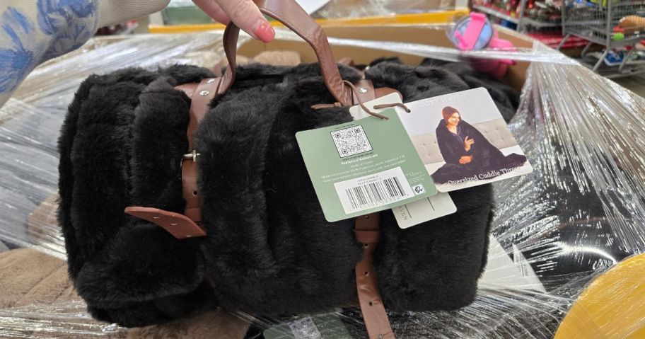 A woman holding a blanket bundled with a leather strap