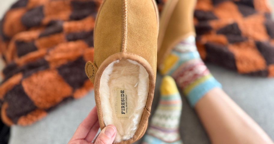 woman holding up pair of Dearfoams Fireside Slippers
