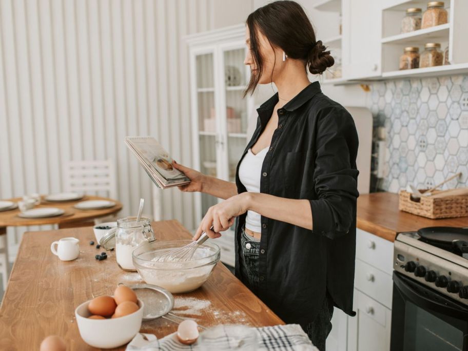 Woman reading from a cookbook while baking