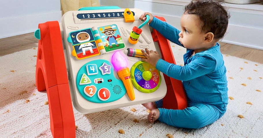 baby sitting on floor playing with fisher-price activity table