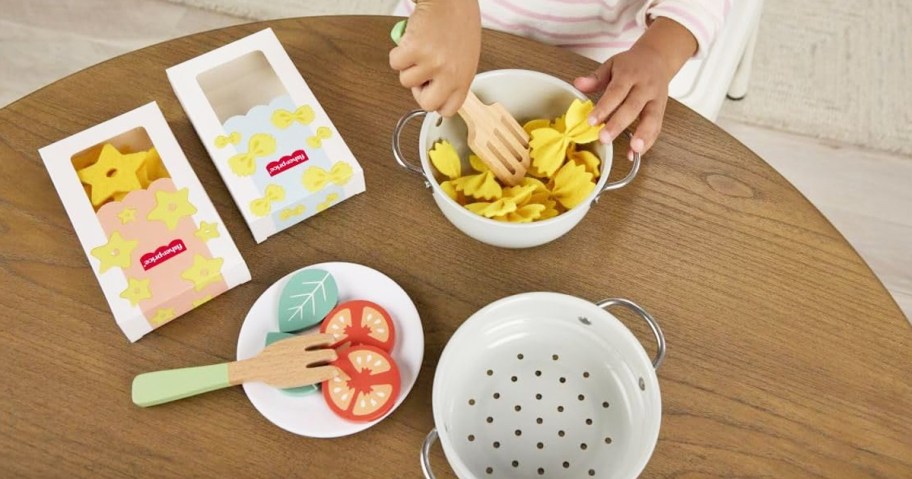 child playing with pretend pasta set on wood table