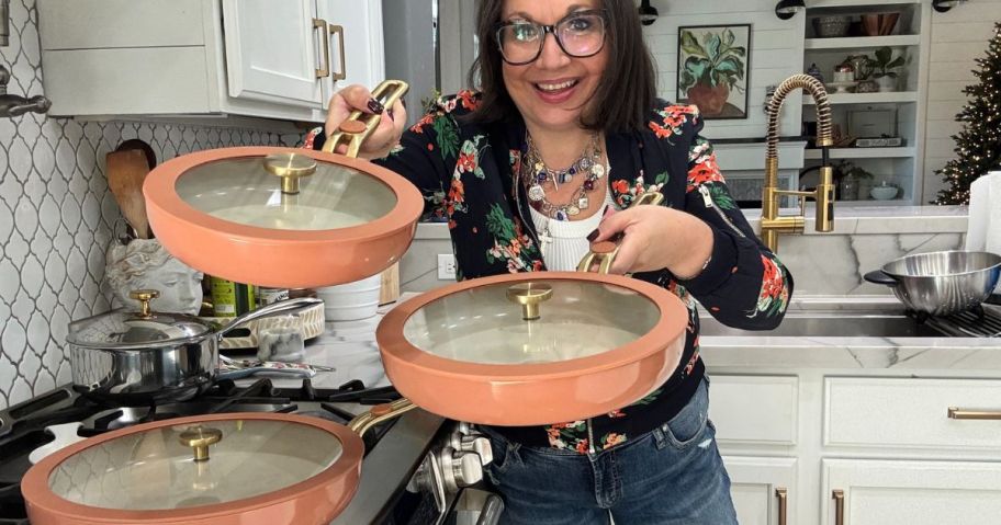 Woman holding pink Our Place pans with gold trimmed lids