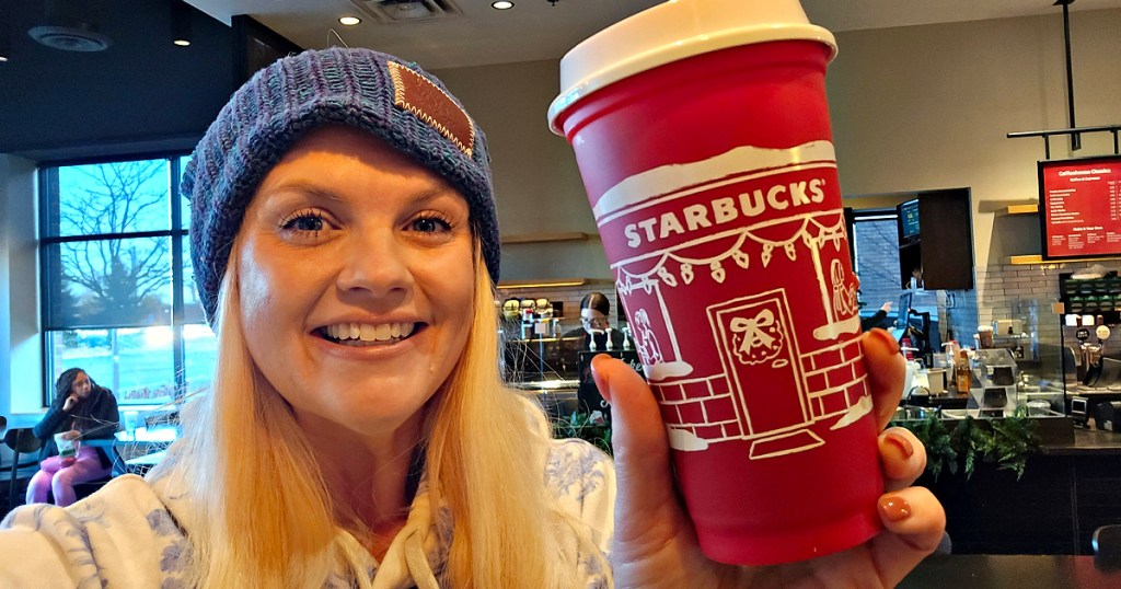 Woman wearing beanie and holding a Starbucks red cup inside store