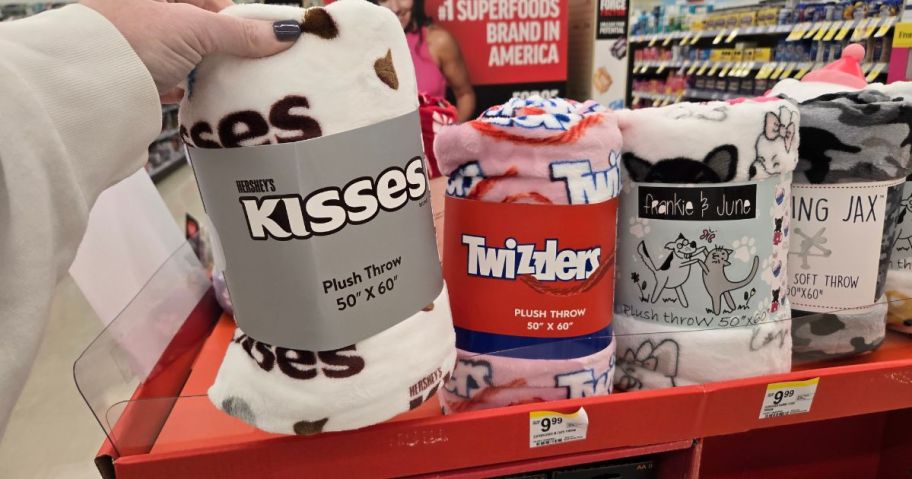 A person holding a candy-themed Walgreens Throw Blanket with others in the background