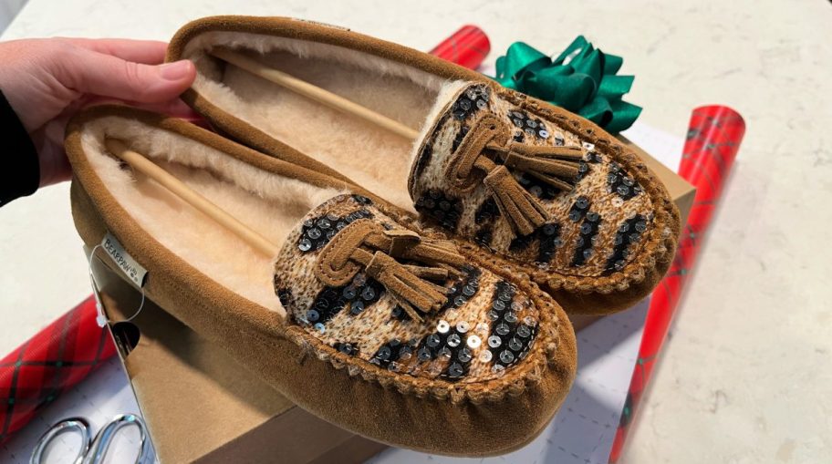 pair of bearpaw slippers sitting on wrapping paper and a box