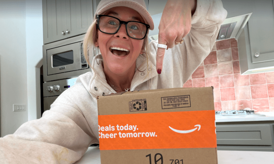 woman holding amazon box smiling in kitchen