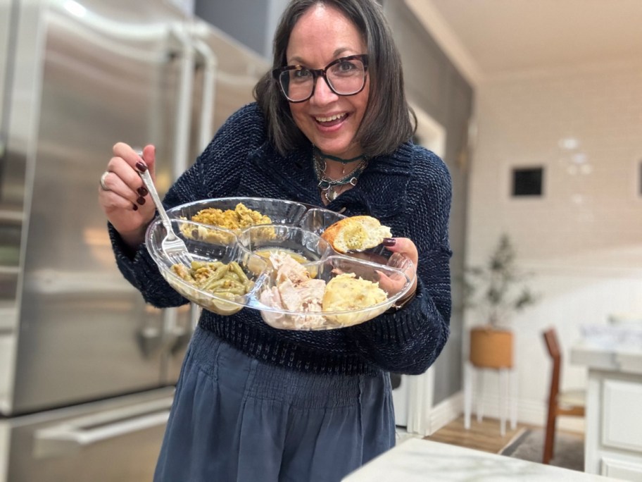 A woman holding a plastic tray full of food.