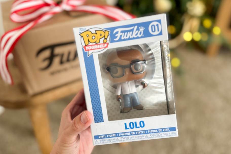 hand holding funko pop figure in box next to cardboard box
