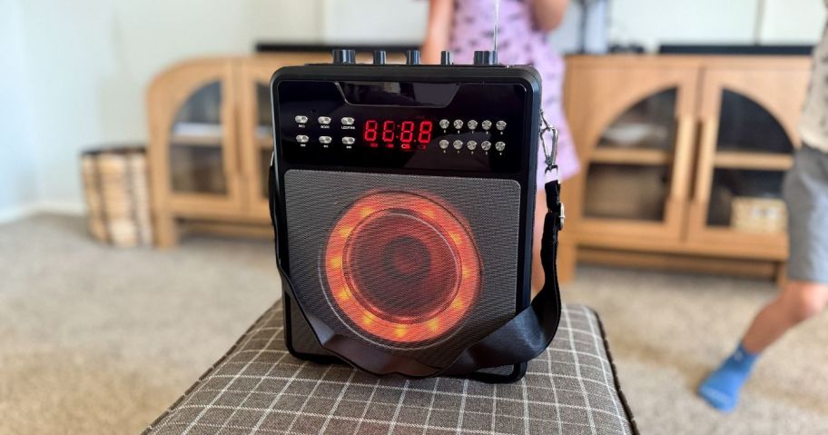 karaoke machine on ottoman with kids singing behind it