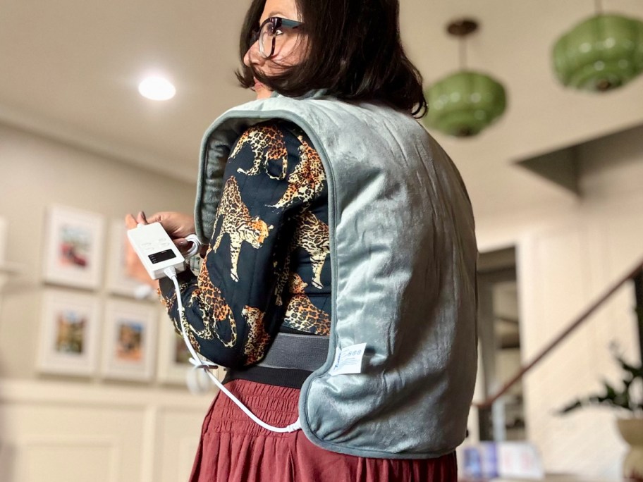 woman wearing blue heating pad on shoulders and back