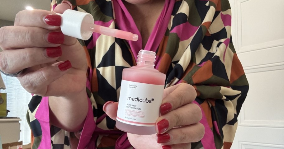 woman holding medicube PDRN pink peptide serum bottle with applicator