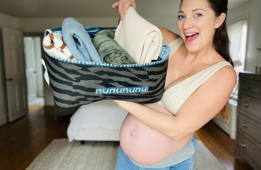 pregnant woman holding up bag of nuuly rental clothes