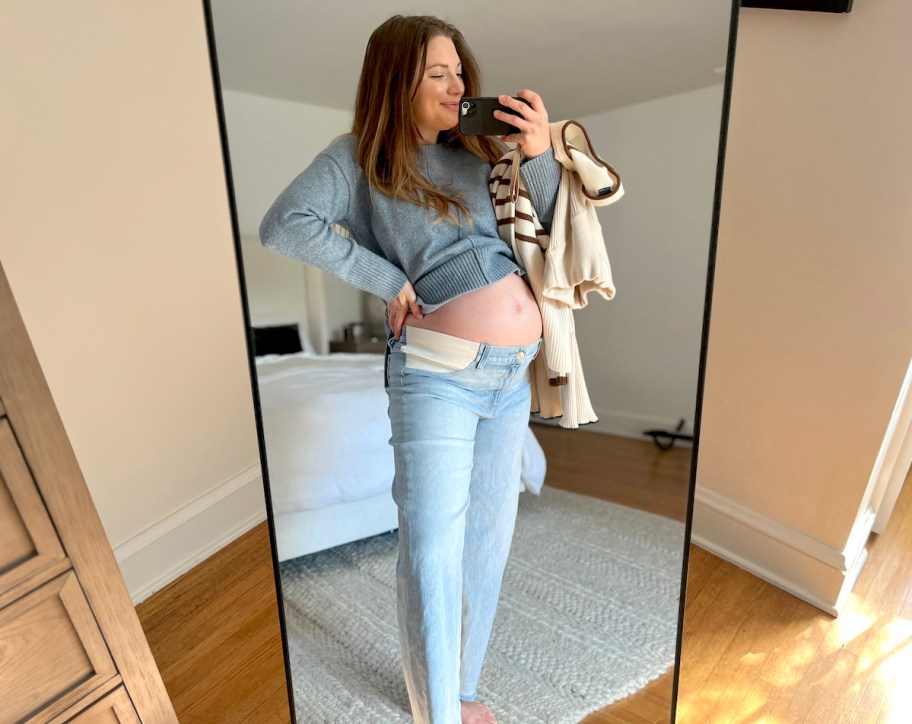 woman taking mirror selfie with pregnant belly showing