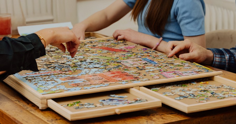 people sitting around a puzzle table