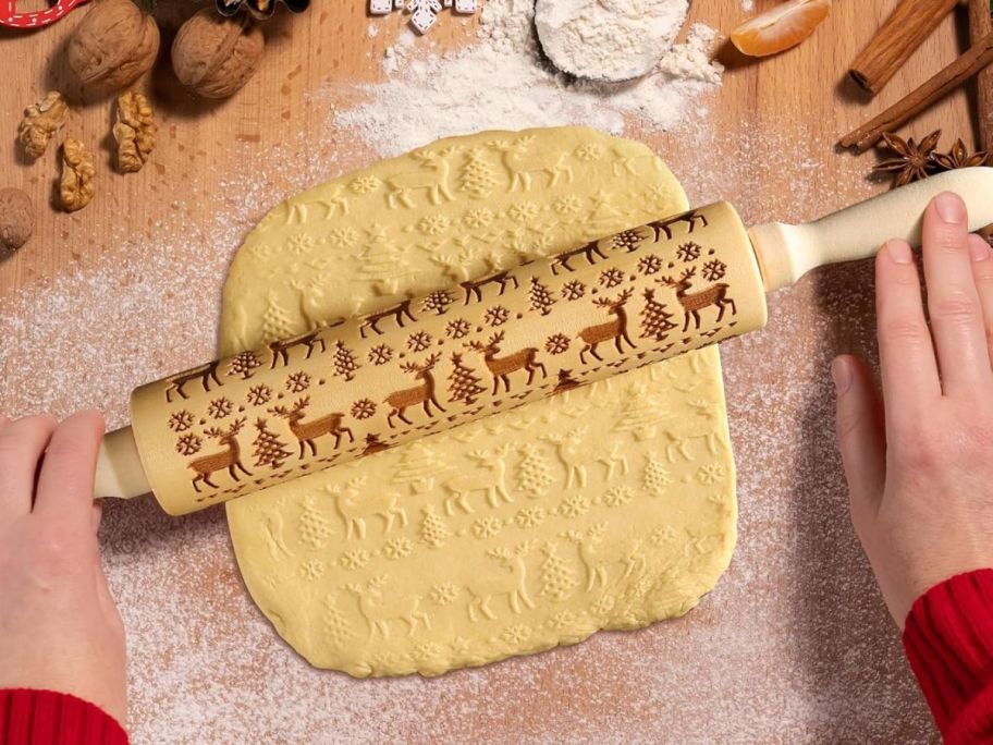 hands rolling elk embossed rolling pin on dough