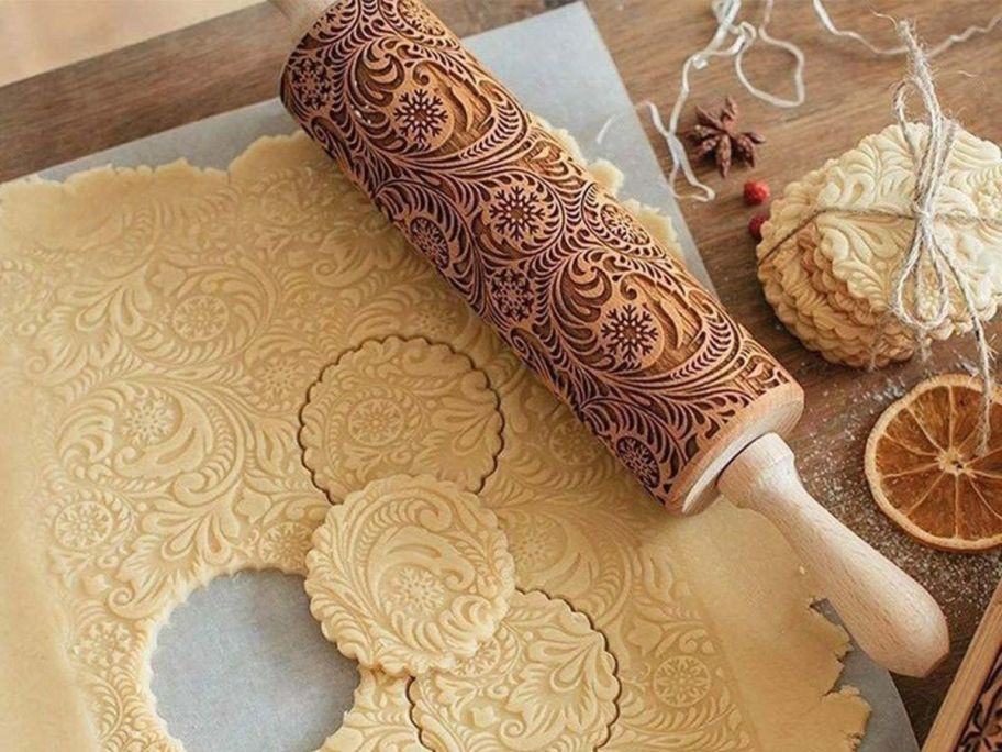 snowflake embossed rolling pin laying next to cookie dough