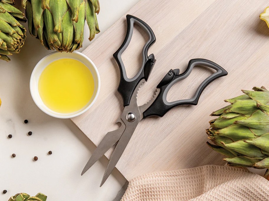bat themed kitchen scissors on a cutting board near artichokes
