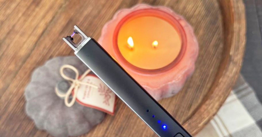 holding a black rechargeable candle lighter with candle in background