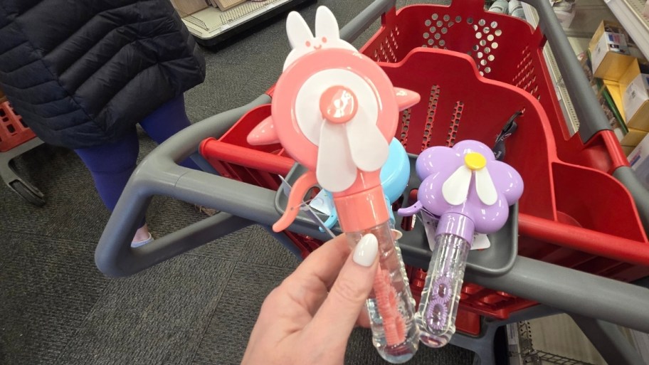 womans hand holding a bubble wand next to two other bubble wands
