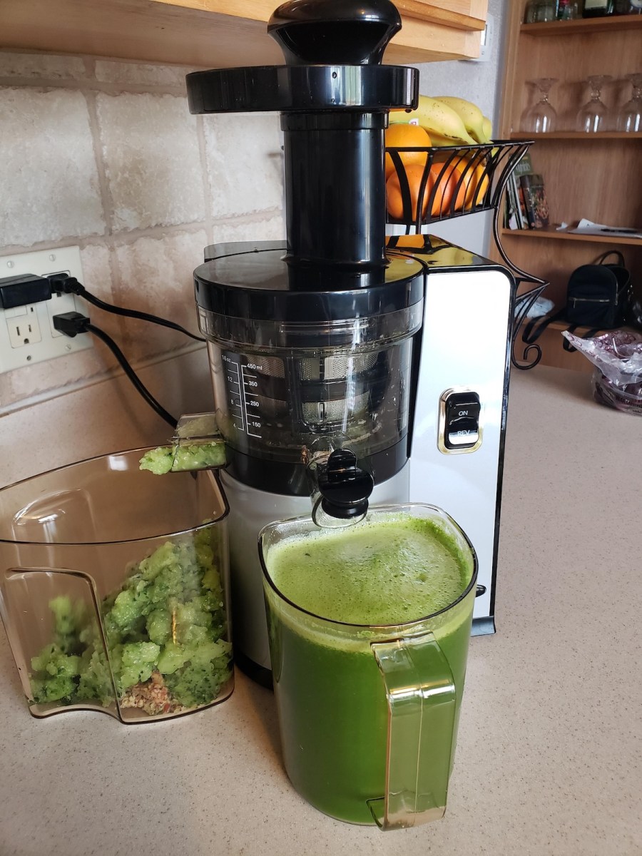 stainless juicer on counter with greens juice