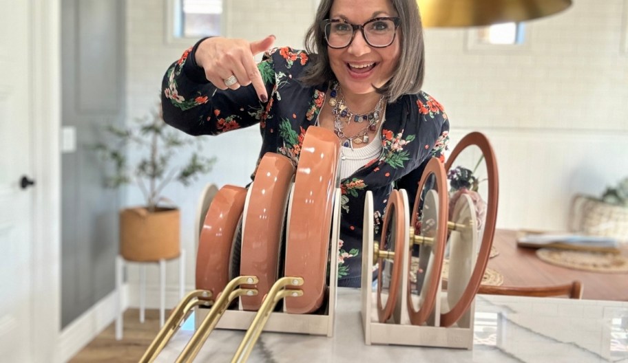 a smiling woman pointing to a cookware set