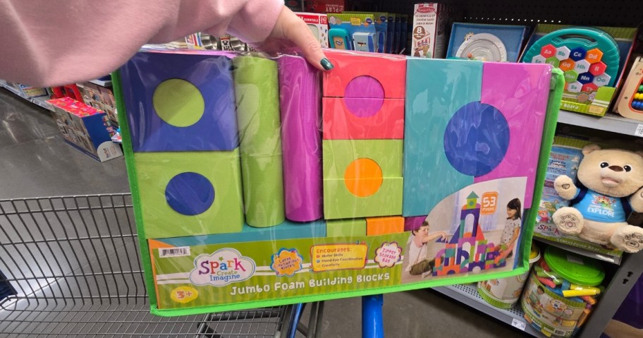 hand holding a pack of foam building blocks in a store aisle