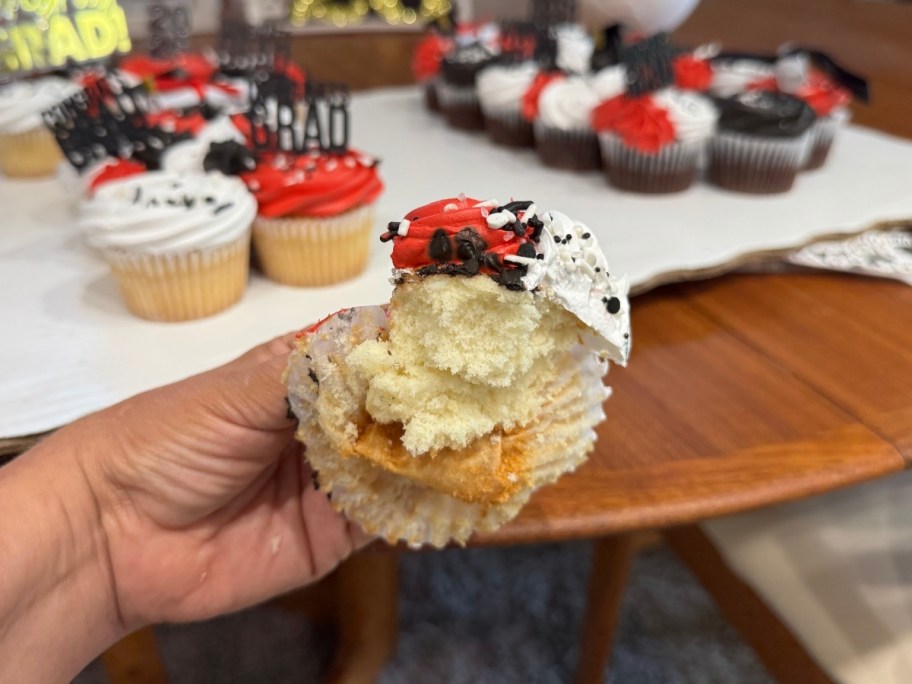 a woman's hand holding a smushed cupcake