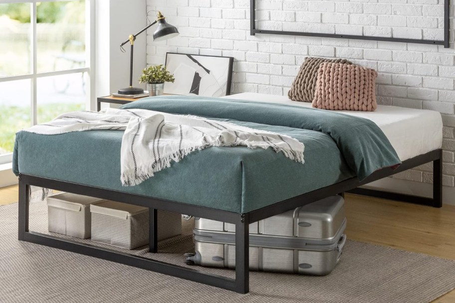 zinus bed frame in a bedroom with a suitcase and storage baskets underneath