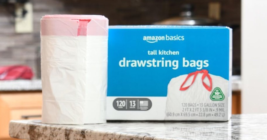 blue box of Amazon Basics 13-Gallon Trash Bags on kitchen counter next to roll of trash bags