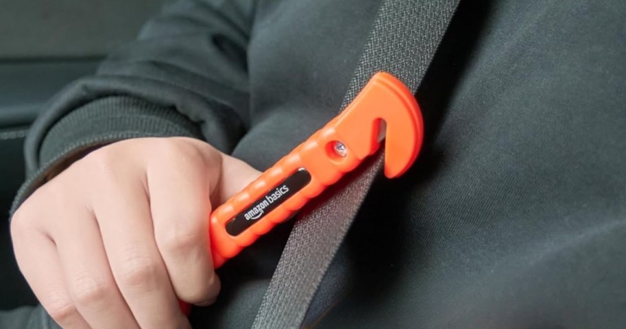 person using amazon basics seatbelt cutter to cut seatbelt in car