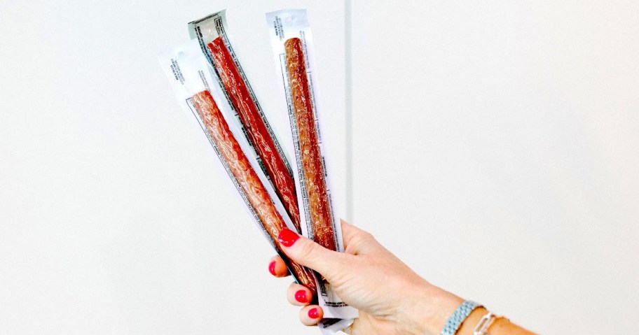 hand holding up 3 Chomps Beef Sticks