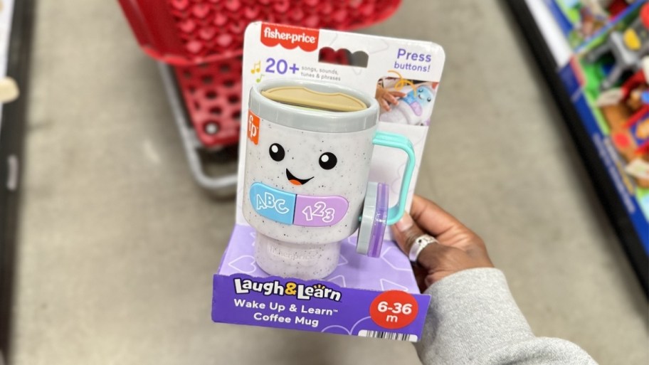 womans hand holding a fisher price laugh and learn coffee mug
