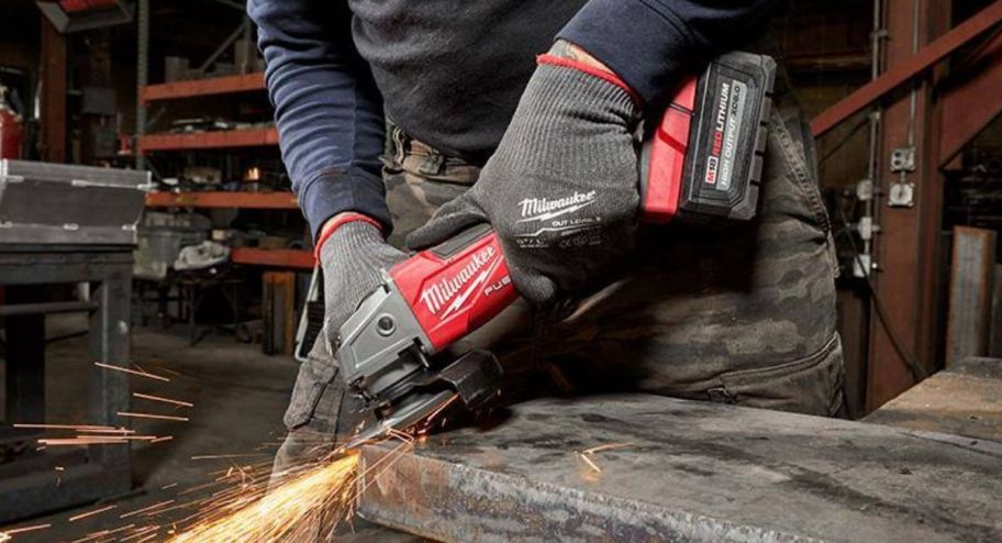 hand holding home depot milwaukee tool while cutting wood