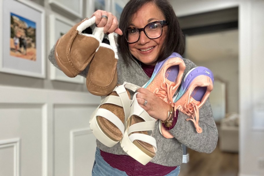 woman holding sandals, sneakers, and loafers