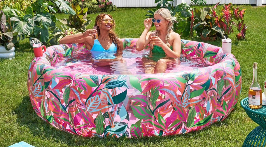 two girls sitting in a pink inflatable pool