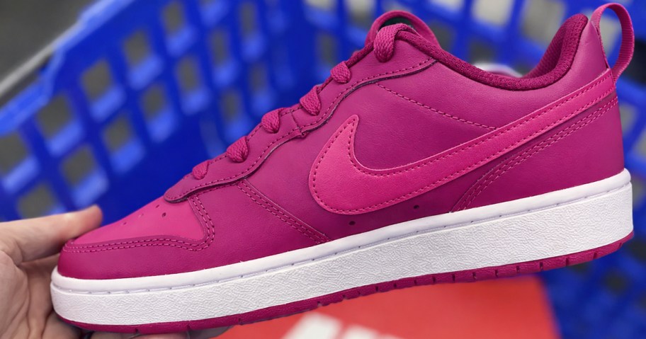 hand holding up a magenta nike sneaker