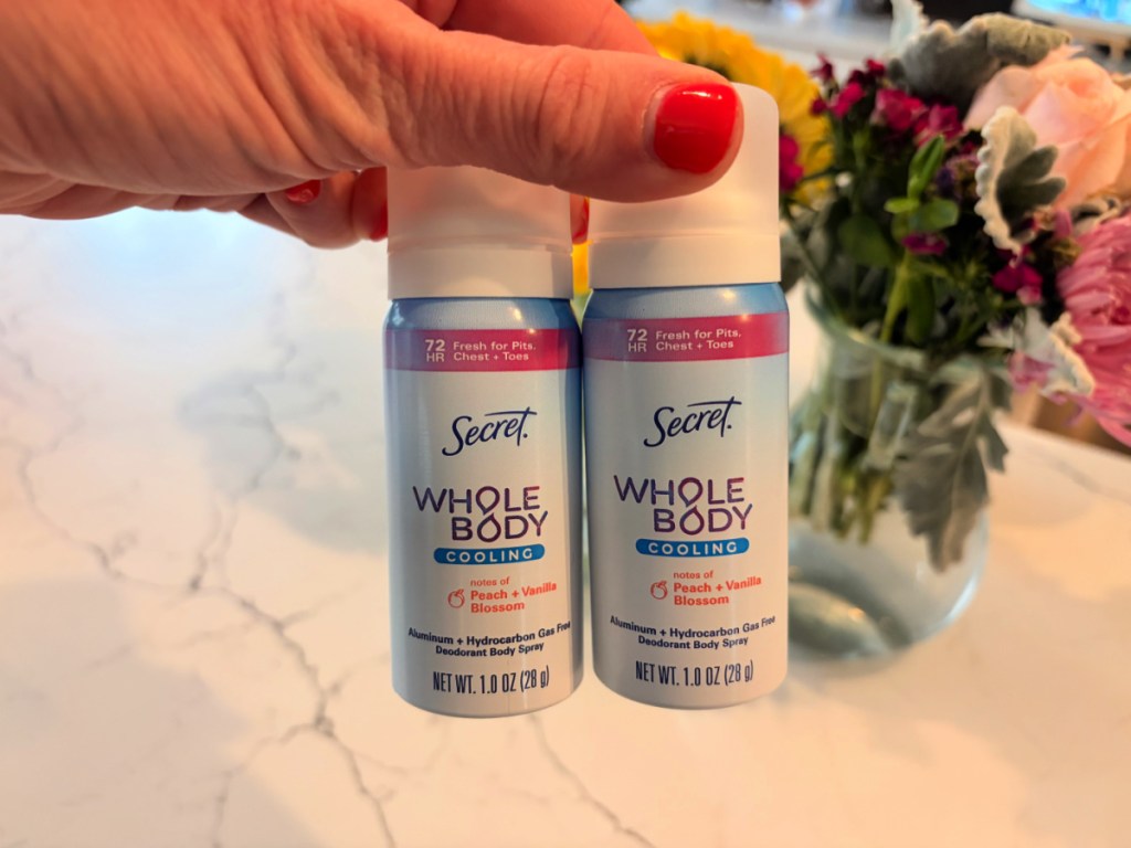 Woman holding up two bottles of secret, whole body cooling deodorant spray