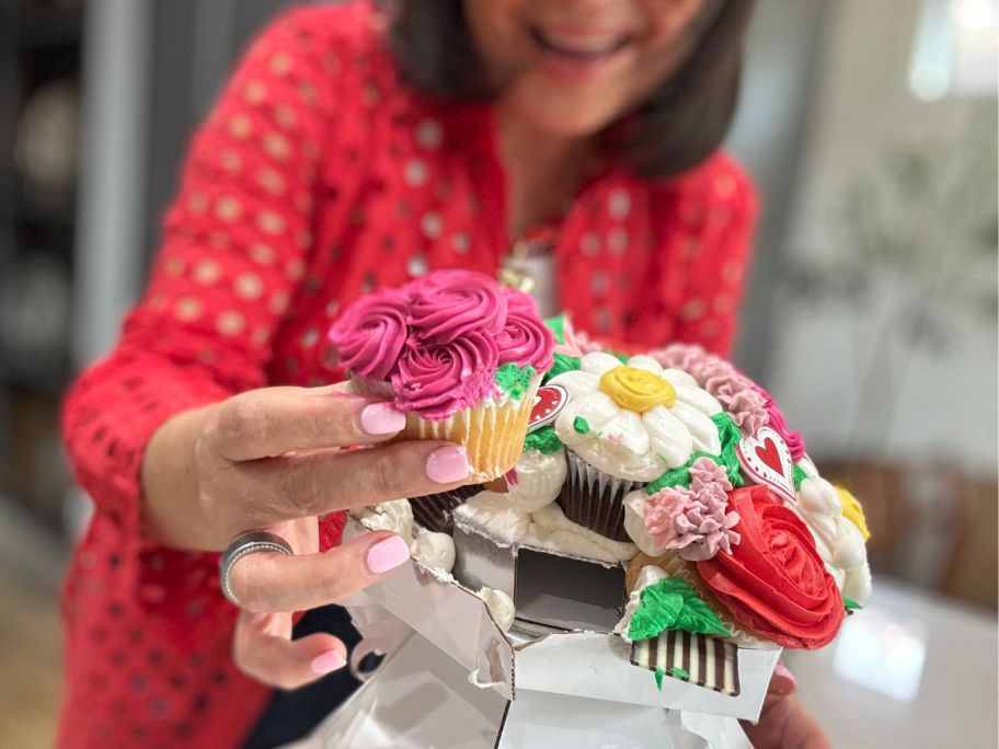 Hand holding a vanilla cupcake from a Walmart cupcake bouquet