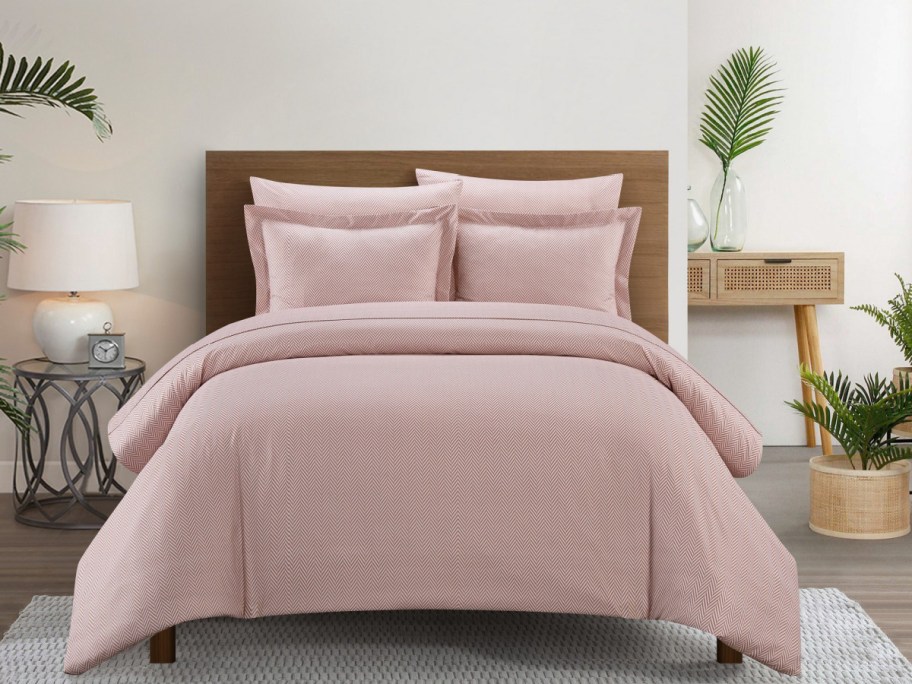 A blush colored Chic Home duvet set on a bed.