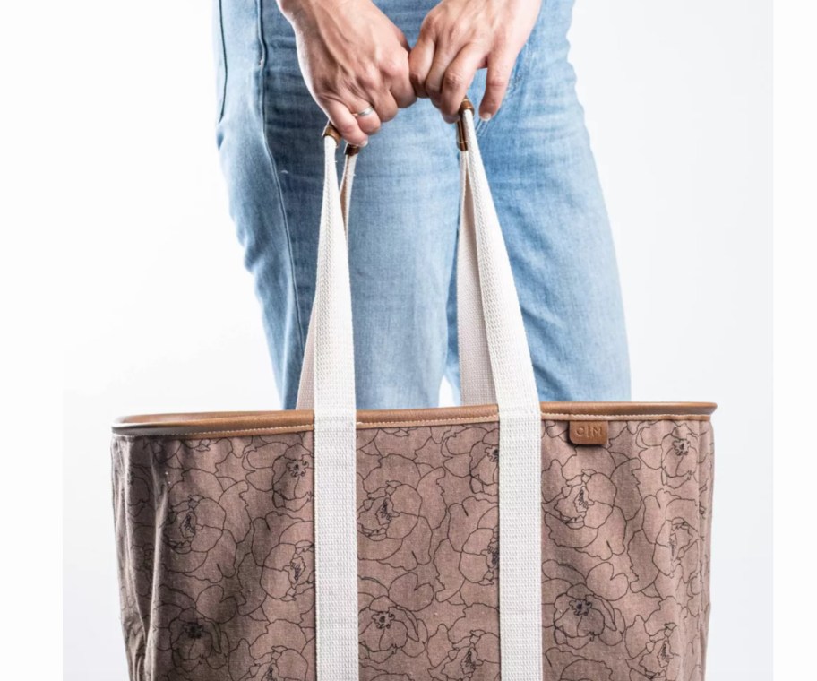 hands holding brown flower printed tote
